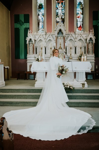 Bride shows off long train/dress bridal gown/dress at alter