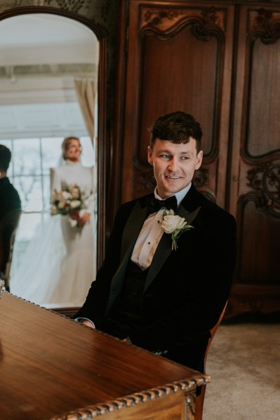 Groom gets ready with bride standing behind him