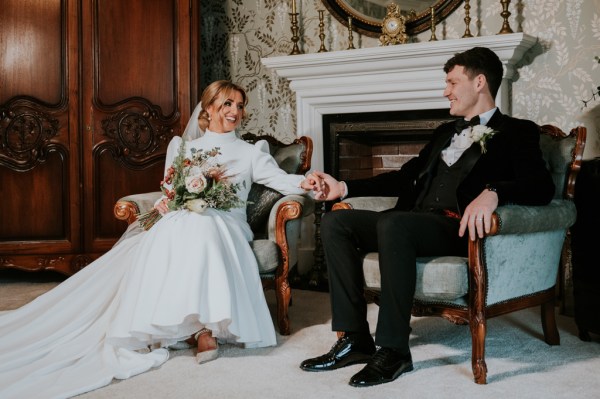 Bride and groom hold hands as bride holds bouquet of flowers