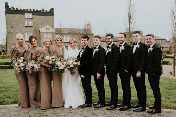 Bride and groom in middle of groomsmen and bridesmaids