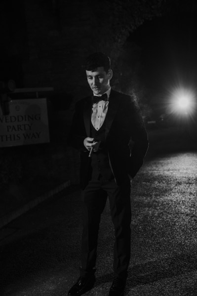 Black and white groom in dark wearing black suit