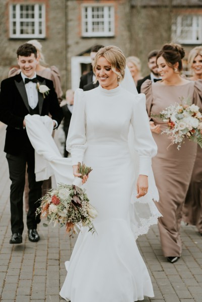 Groom holding brides train dress with bridesmaids holding bouquet/flowers