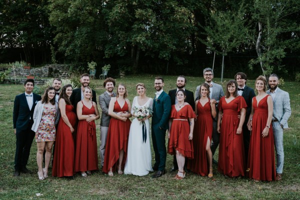 Bride groom groomsmen and bridesmaids pose for a picture on the grass