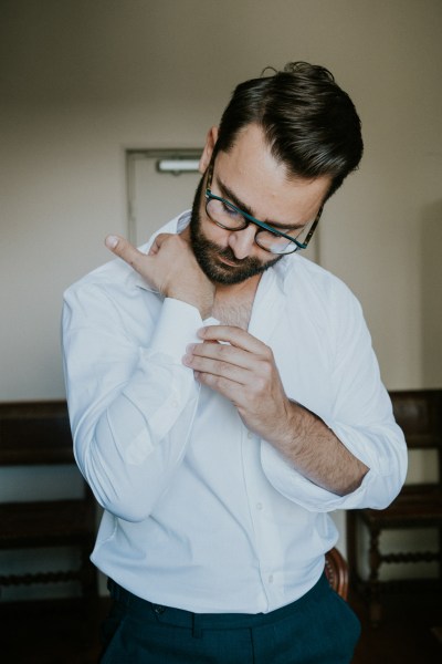 Groom buttons his wedding shirt