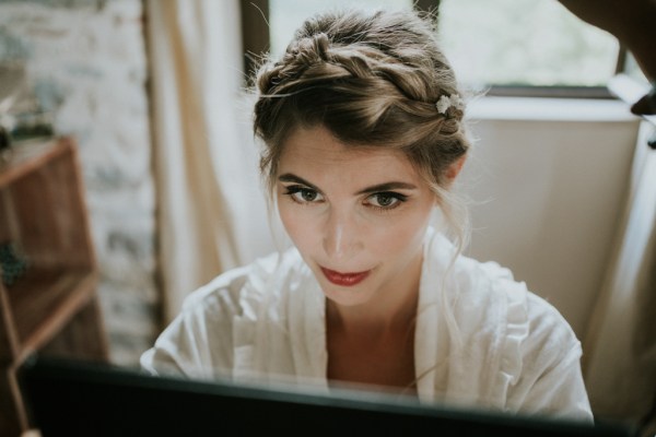 Bride looks in reflection as she's getting hair and makeup done