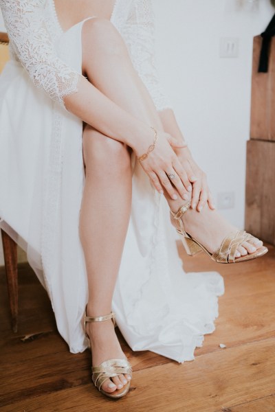 Bride puts on her wedding heels as she sits on chair