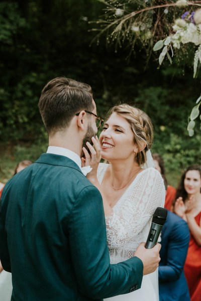 Bride places hand on groom cheek smiling