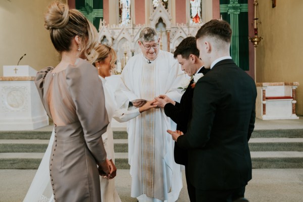 Priest bridesmaids and two men in suits