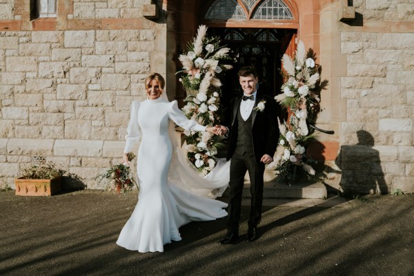 Bride and groom holding hands outside of church