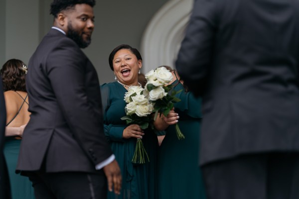 Guests holding white flowers smile