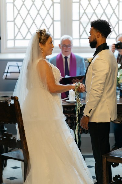 Bride and groom stand at alter with priest