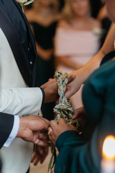 Celebrant bounds bride and groom together with ribbon