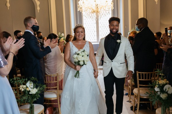 Bride and groom exit ceremony guests clapping