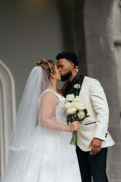 Bride and groom kiss she holds bouquet