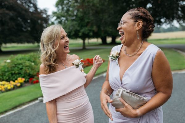 Two mothers laughing outside wedding venue