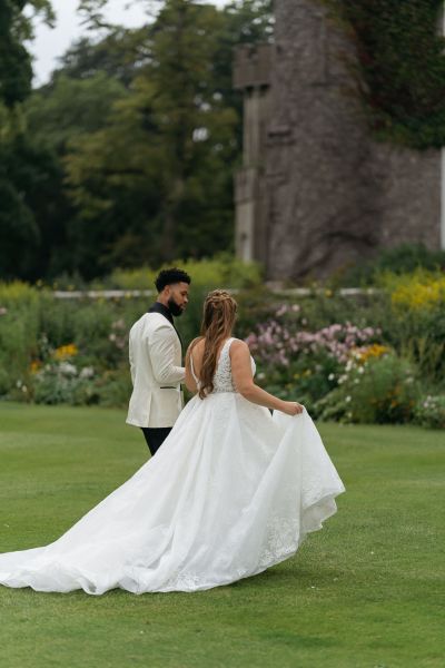 Bride and groom walk along the grass to wedding venue