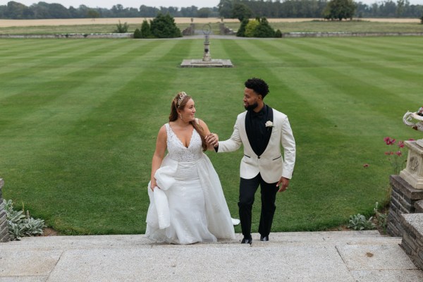 Bride and groom walk up the steps to wedding veneu