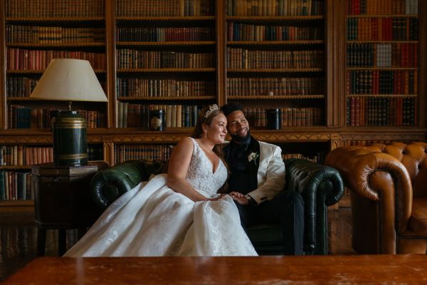 Bride and groom look out the window bookcase behind them library room