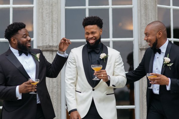 Groom holding orange cocktail with friends/groomsmen