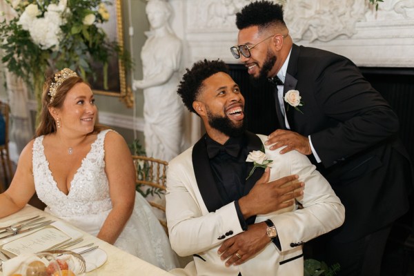 Bride groom and friend laugh at table