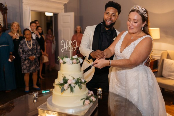 Bride and groom cut the white wedding cake together