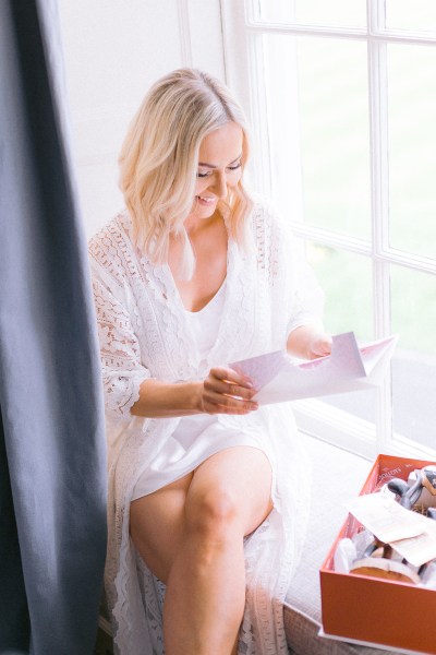 Bride reading letter from groom at windowsill