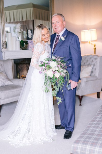 Father kisses daughter bride on the cheek she holds flowers