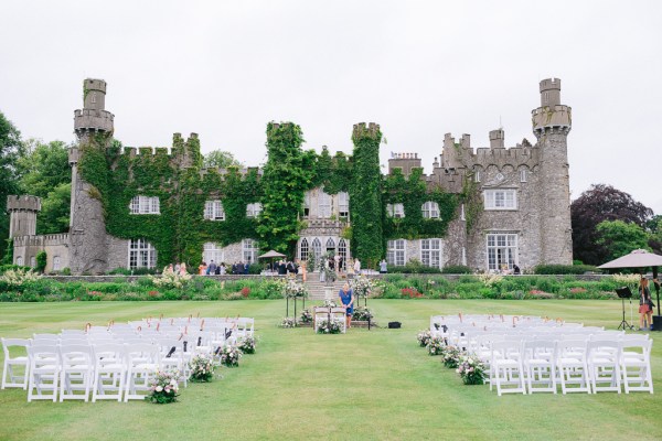 Empty ceremony detail seating for wedding in front of castle covered in ivy