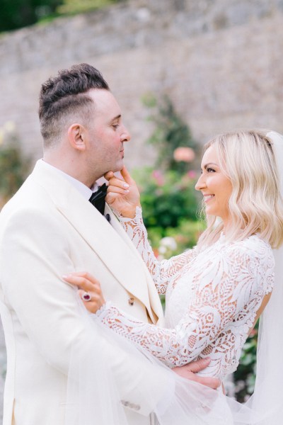 Bride and groom embrace and hug in garden