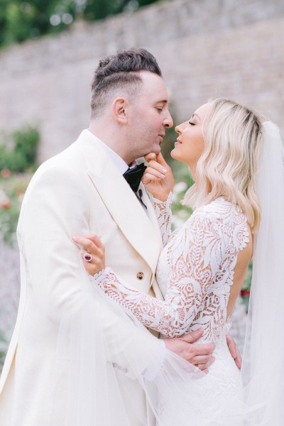 Bride and groom embrace and hug in garden going in for a kiss