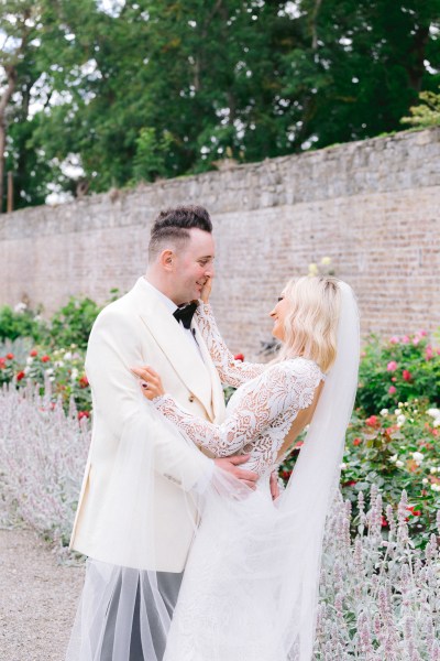 Bride and groom embrace and hug in garden