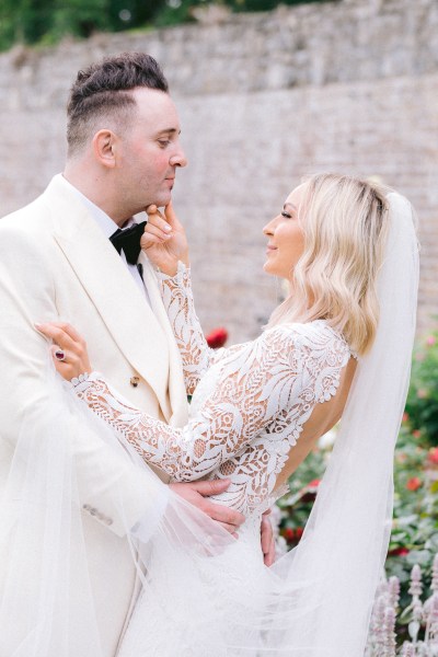 Bride and groom embrace and hug in garden