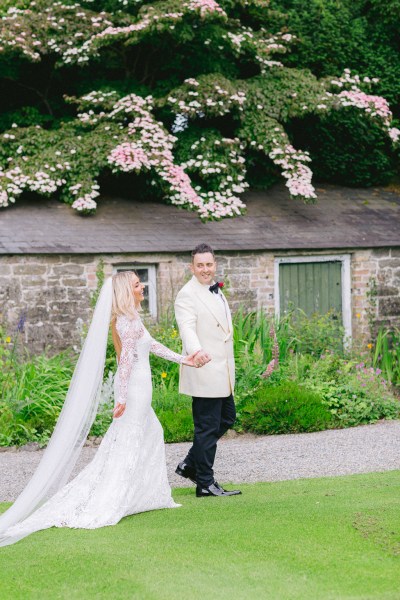 Bride and groom walk along pathway in garden