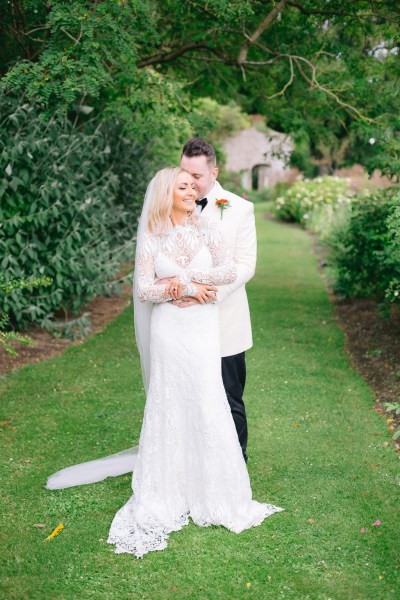 Hug from behind from groom to bride on grass garden