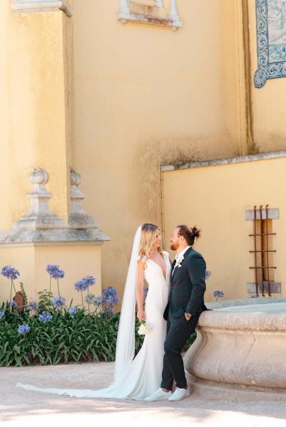 Bride and groom lean against wall to resort venue