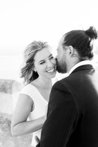 Bride smiles at groom during sunset on balcony black and white image