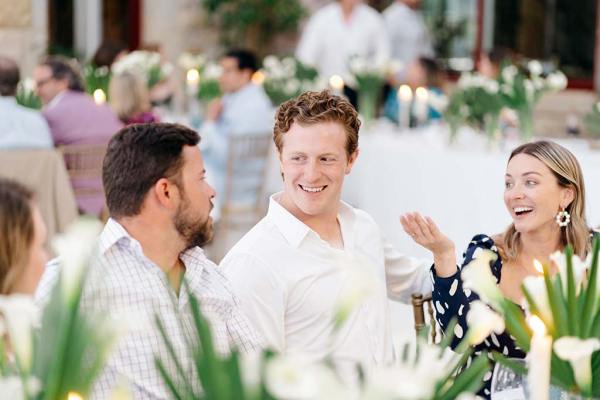 Two men wearing white shirts and a woman are chatting at the table