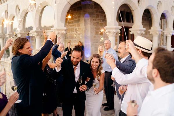 Sparkers are lit by guests are they hold them up over bride and groom exiting church cathedral