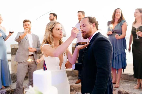 Bride feeding her groom/husband the white wedding cake