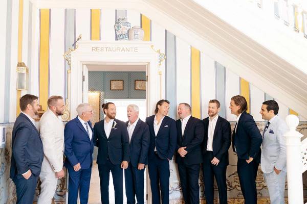 Groom groomsmen family members and father pose for a photo