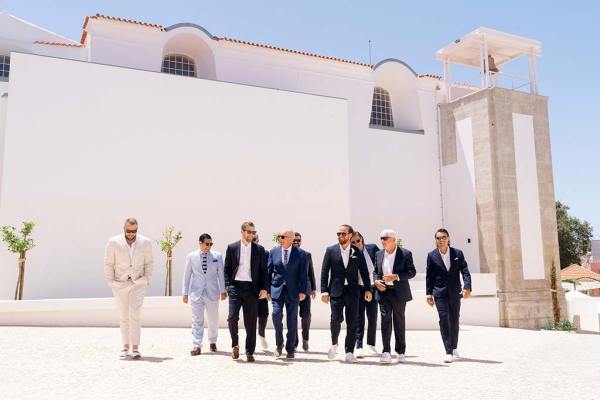 Groom groomsmen family members and father pose for a photo exterior shot as they walk