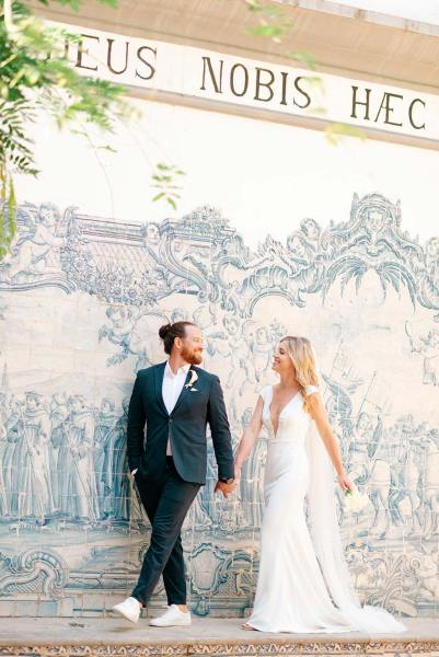 Bride and groom hold hands in front of sketch portrait painting