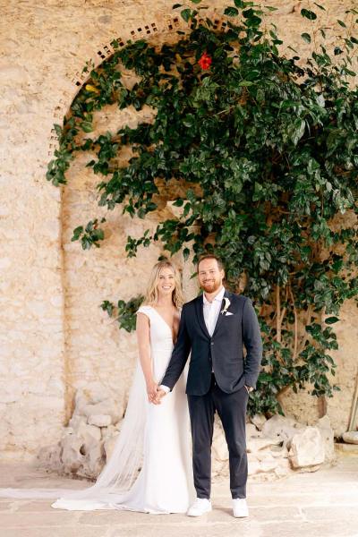 Bride and groom hold hands in front of a tree