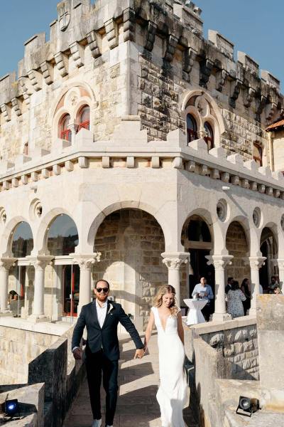 Bride and groom walking away from venue pillars in background