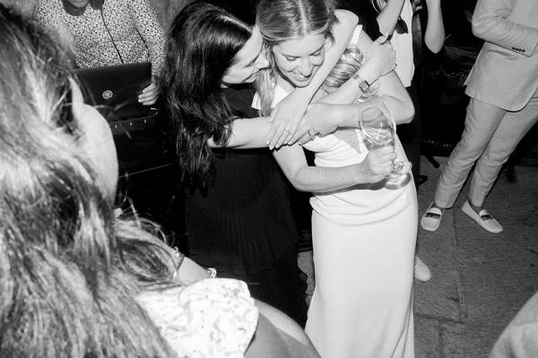 Black and white image of woman hugging bride