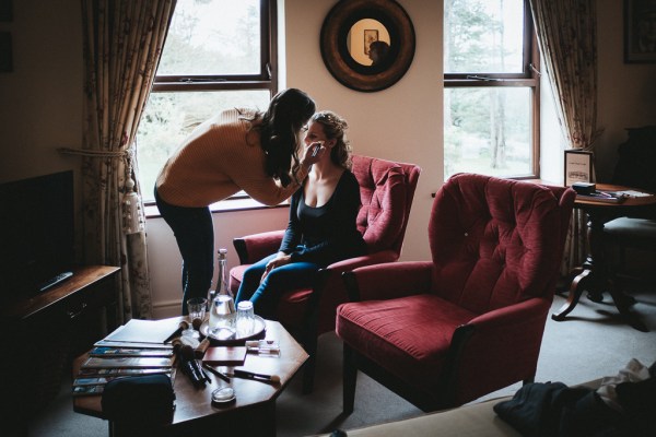 MUA doing brides makeup on red sofa chairs