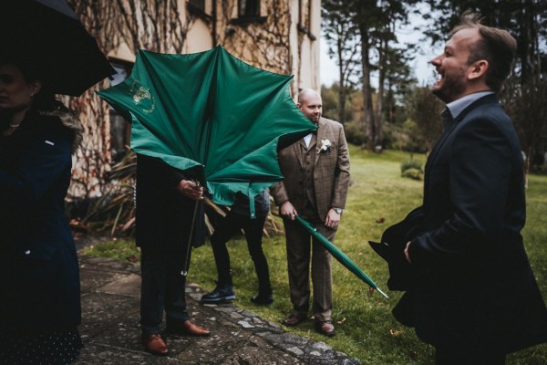 Green umbrella blows in the air due to the wind