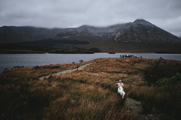 Bride follows the trail of guests heading towards cliff ceremony