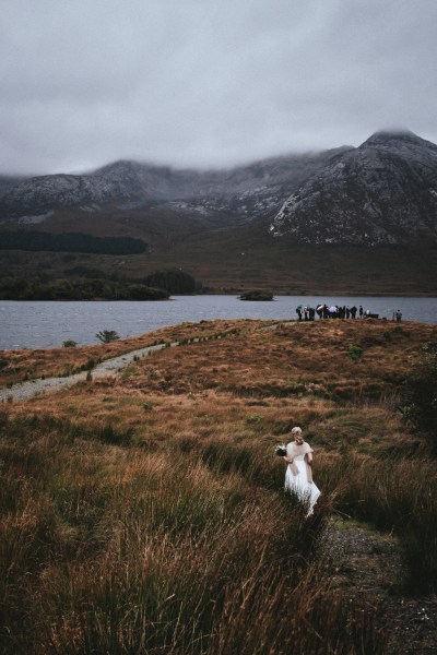 Bride follows the trail of guests heading towards cliff ceremony