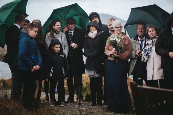 View of family standing in the rain holding up umbrellas